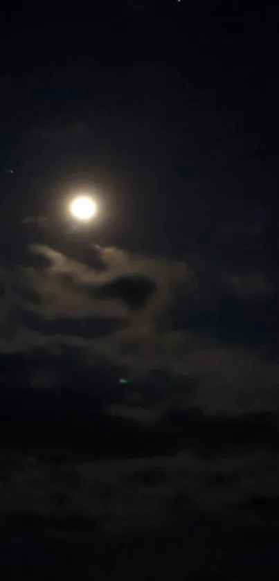 Bright moon against dark night sky with clouds.