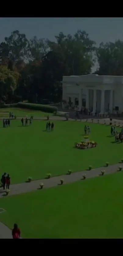 A lush green garden with a white building behind and scattered visitors.