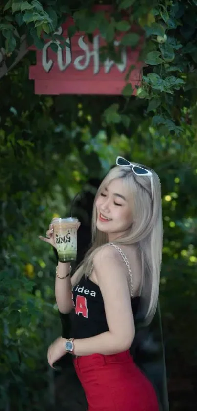 Woman enjoying a drink in a lush green setting.