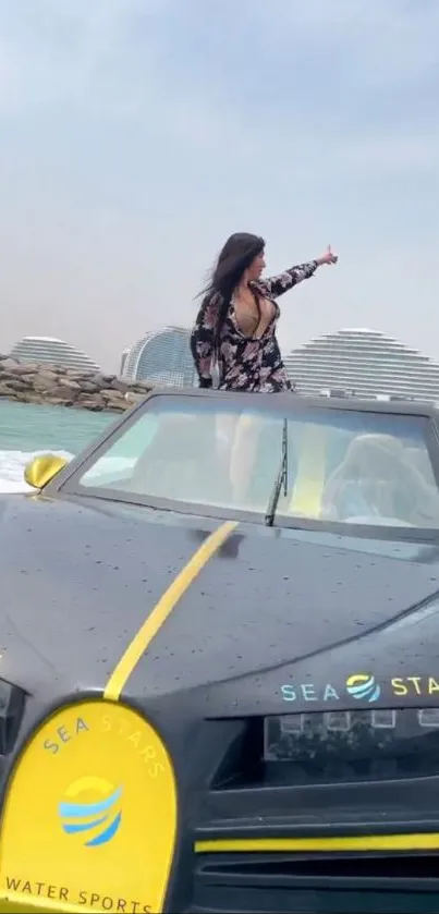 Person in car with ocean backdrop and buildings.