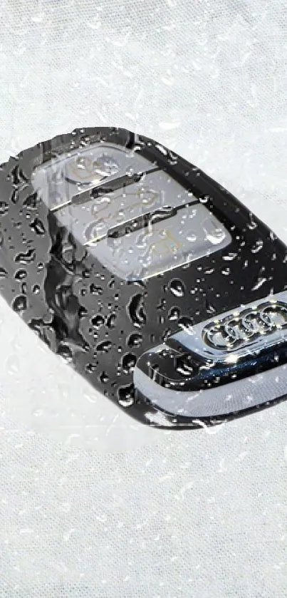 Black luxury car key with raindrops on a textured surface.