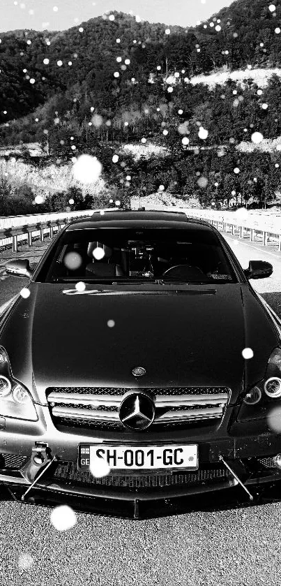 Black luxury car with mountain backdrop.