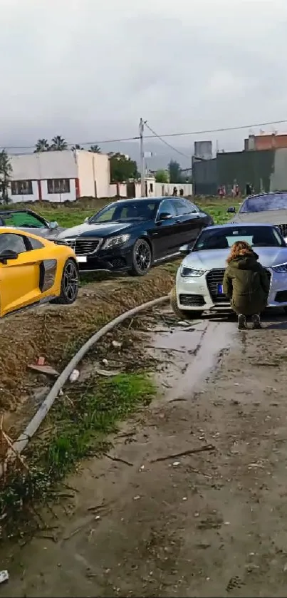 Luxury cars lined on a rugged road with a person in the background.