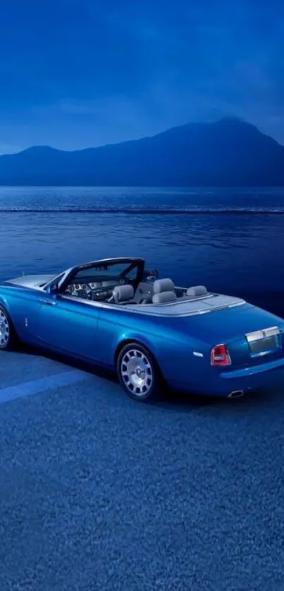 Convertible car by a serene blue sea with mountains in the background.