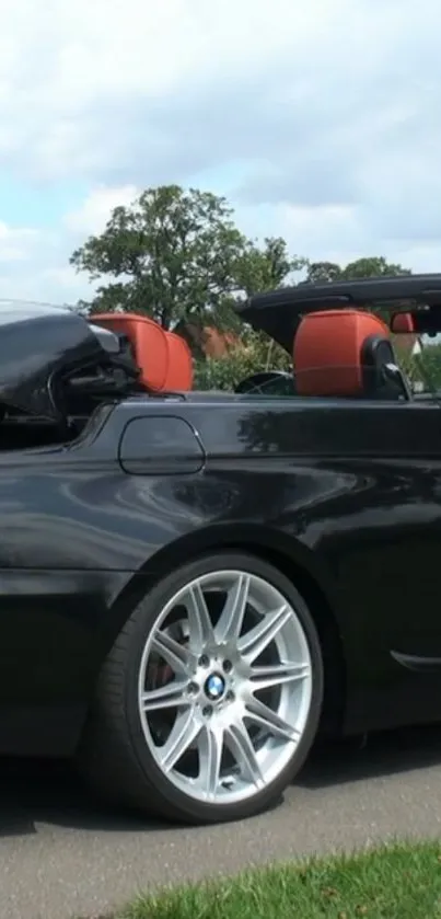 Black luxury convertible car with orange seats.