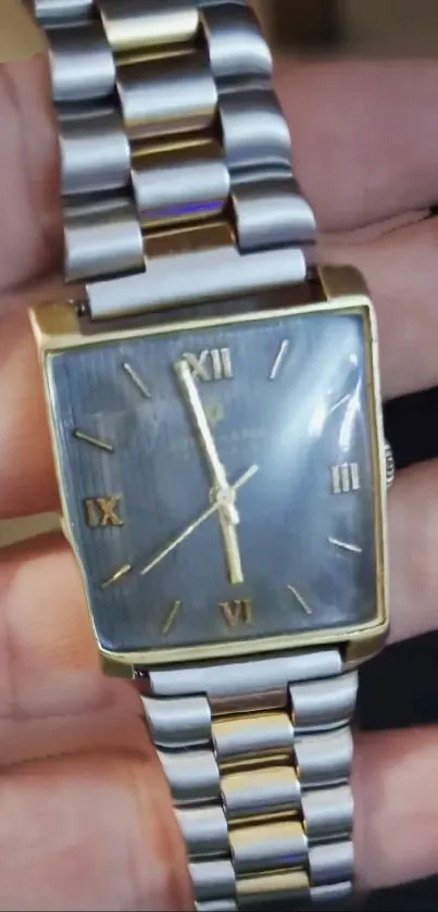 Close-up of elegant gold wristwatch with Roman numerals and metallic band.