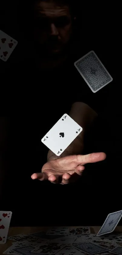 Hand holding floating playing cards in darkness.