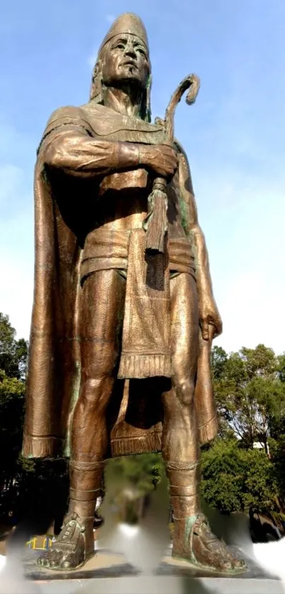 Majestic bronze statue under a clear blue sky with lush green surroundings.