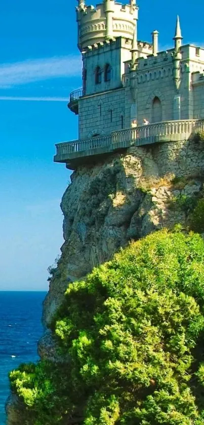 Majestic castle on ocean cliff with greenery and clear blue sky.