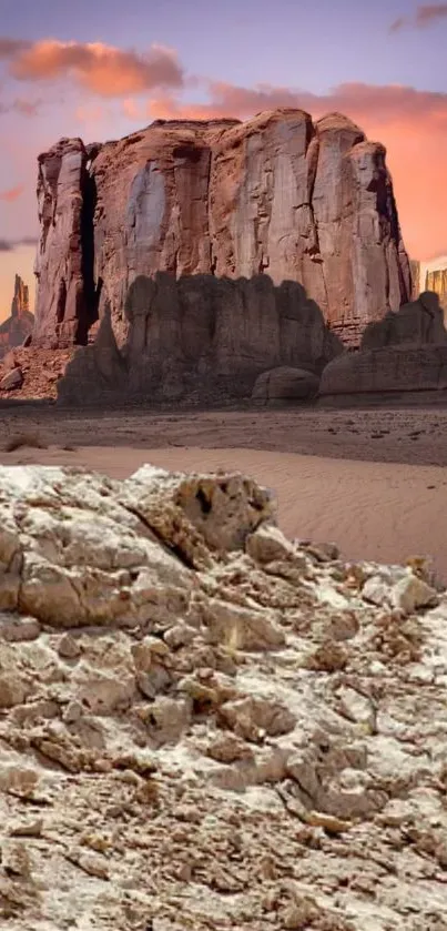 Desert landscape with towering rock formations under a colorful sky.