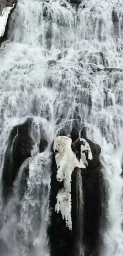 Majestic frozen waterfall cascading over rocks in a serene winter scene.