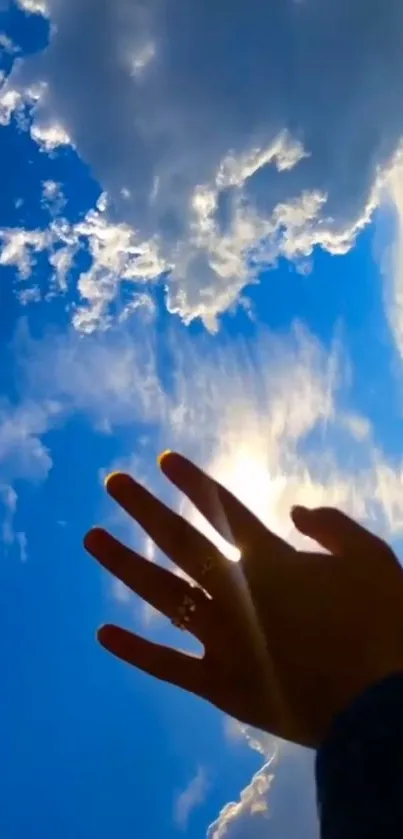 Hand reaching out to bright sky with clouds.