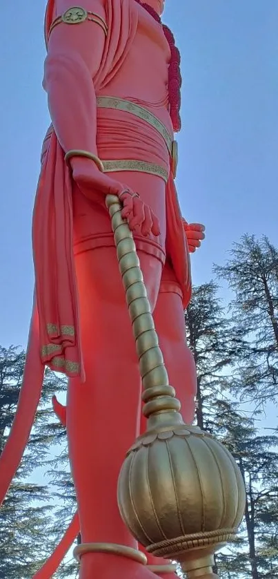 Majestic red Hanuman statue with trees.