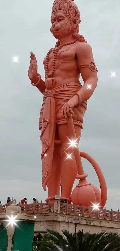 Majestic Hanuman statue with lush greenery and cloudy sky background.