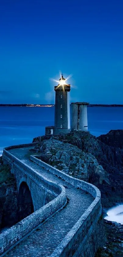 Majestic lighthouse with bright light at ocean dusk under dark blue sky.