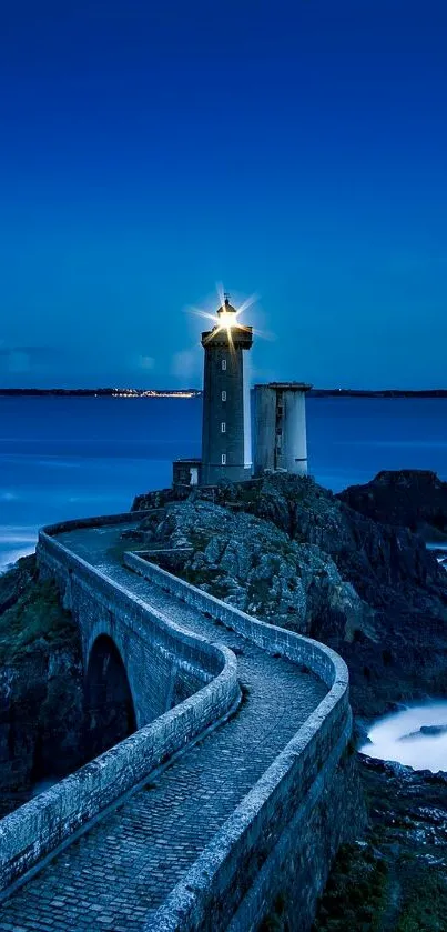 A lighthouse shines brightly under a dark blue ocean sky with rocky coastline.