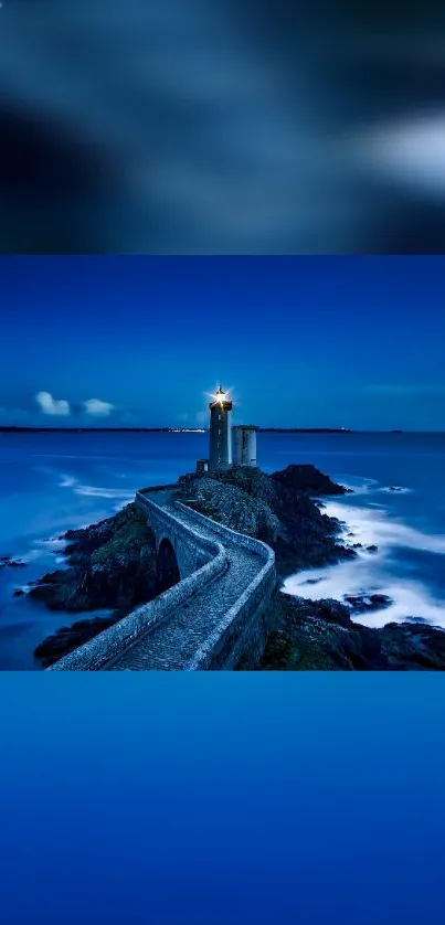 Lighthouse on a coastal pathway under a starry blue night sky.