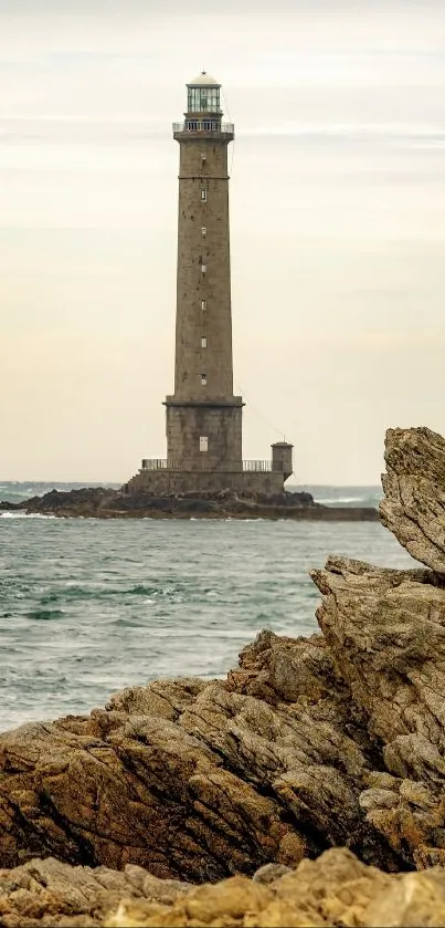 Lone lighthouse stands amid rocky coastline by the sea.