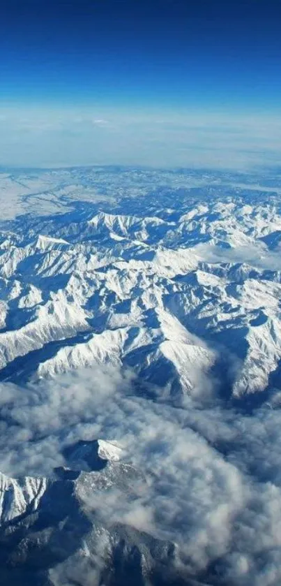 Aerial shot of snow-capped mountains under a clear blue sky.