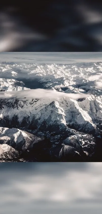 Aerial view of snow-capped mountains with cloudy sky.