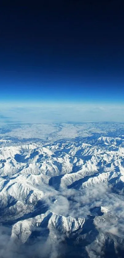 Aerial view of snow-capped mountains beneath a clear, deep blue sky.