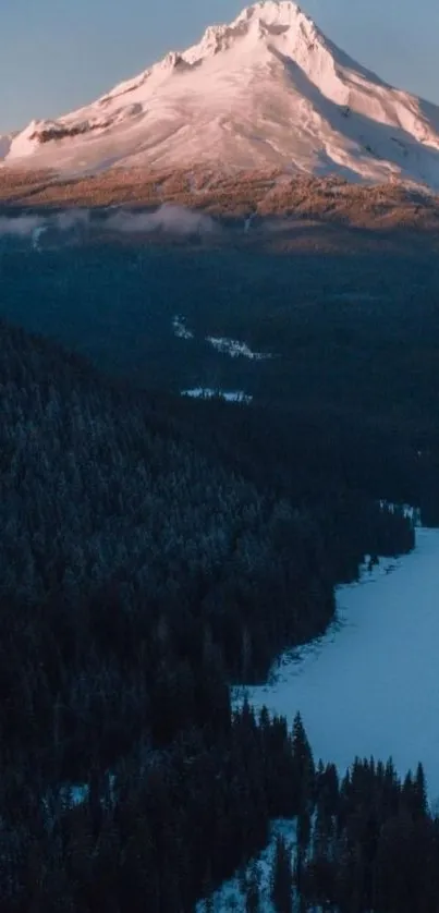 Snow-capped mountain at dusk with forest and river.