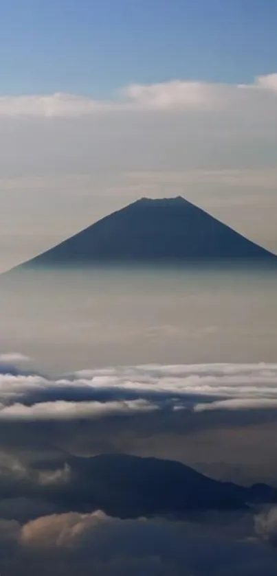 Mountain peak enveloped in mist with gentle clouds in a tranquil scene.