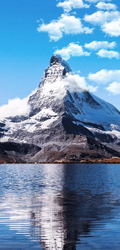 Majestic snowy mountain reflecting in a clear blue lake under a sky with white clouds.