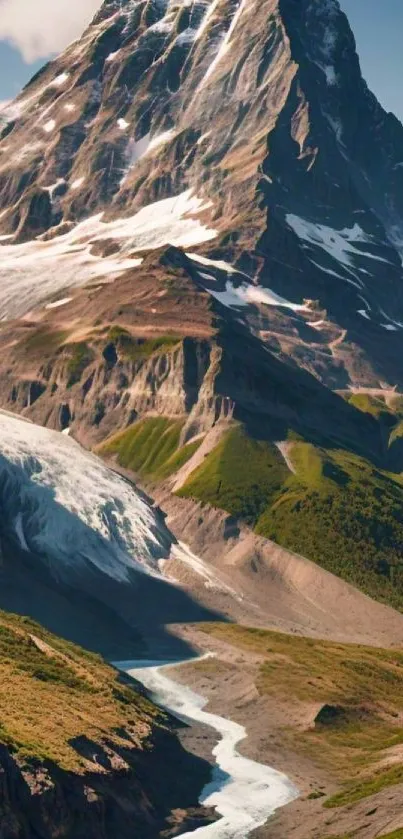 Snowy mountain with green valleys under clear blue sky.