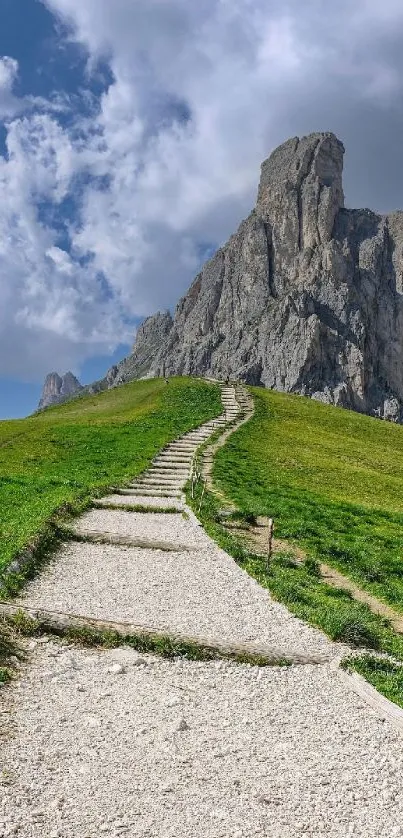 Mountain pathway leading to a tall rock formation under a cloudy sky.