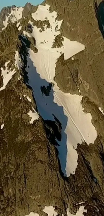 Rugged mountain peaks with snow patches in sunlight.