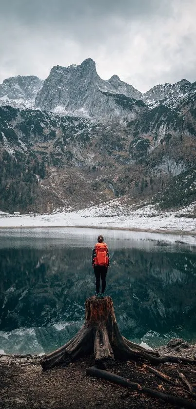 A person standing by a lake with majestic mountains in the background.