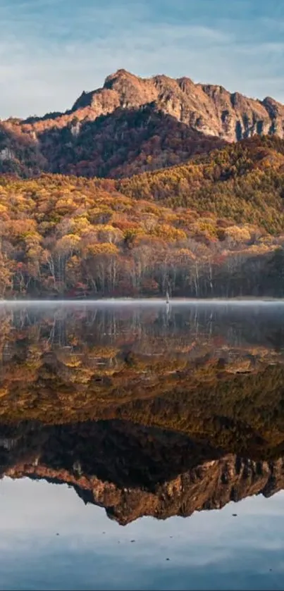 Mountain and lake reflection with autumn trees, under a clear sky.