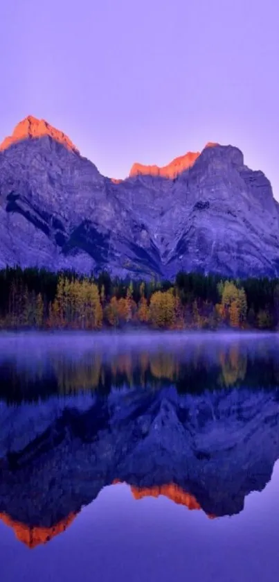 Majestic mountains reflected in calm lake under a vibrant purple sky at sunrise.