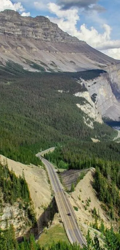 Scenic mountain road through lush forests under blue sky.