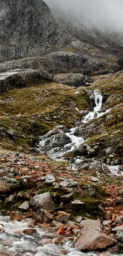 Misty mountain with flowing stream and rocks undercloud.