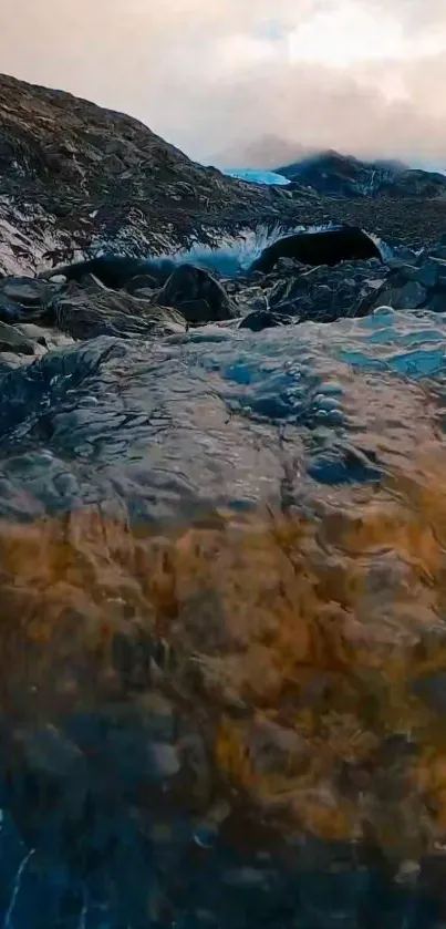 A serene mountain stream flowing over rocks under a cloudy sky.