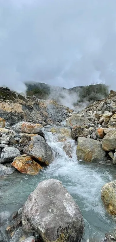 Mountain stream flows through rocky terrain under misty skies.