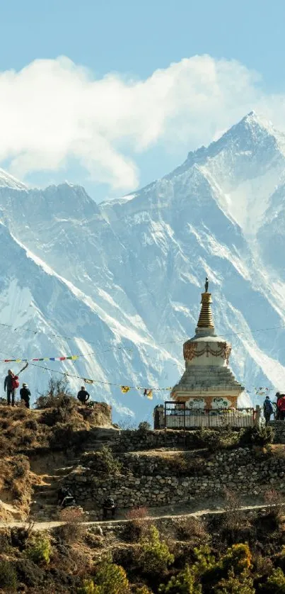 Stupa with snow-capped mountains in the background, under a clear blue sky.