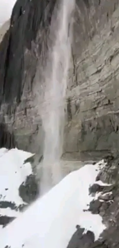 Majestic waterfall on rocky mountain wallpaper with snow.