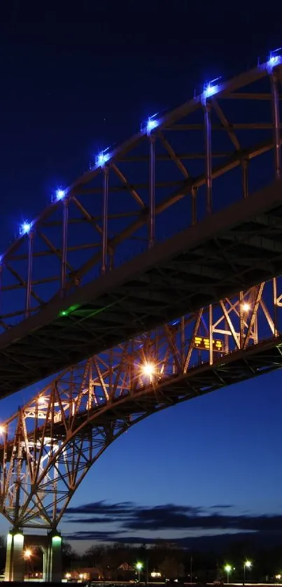 Illuminated bridge at night with stunning blue sky.