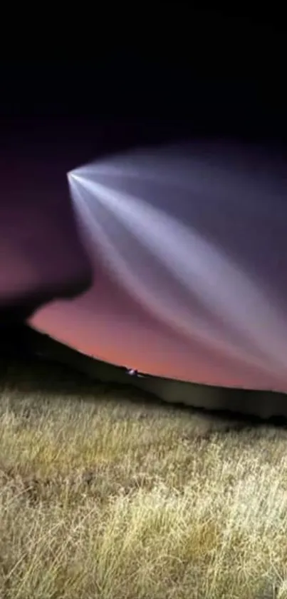 Mystical beam of light in dark sky over grassy landscape.