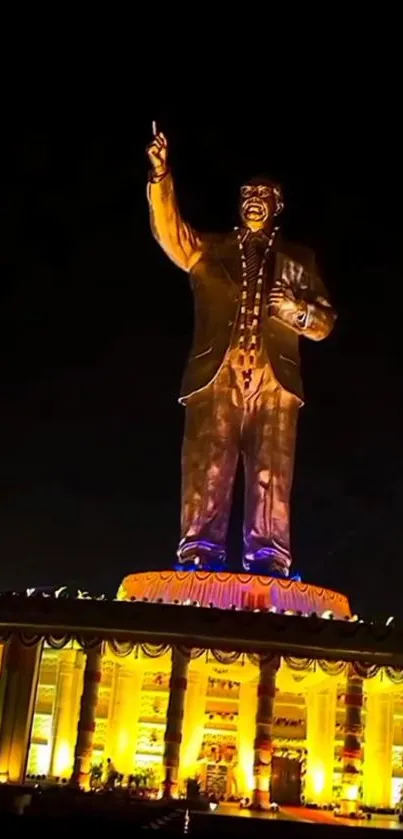 Bronze statue illuminated at night with glowing architecture.