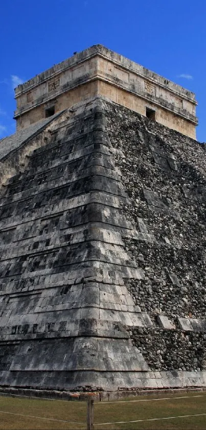 Ancient stone pyramid beneath a vibrant blue sky with scattered clouds.