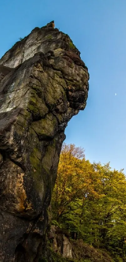 Tall rock formations against a bright blue sky with greenery at the base.