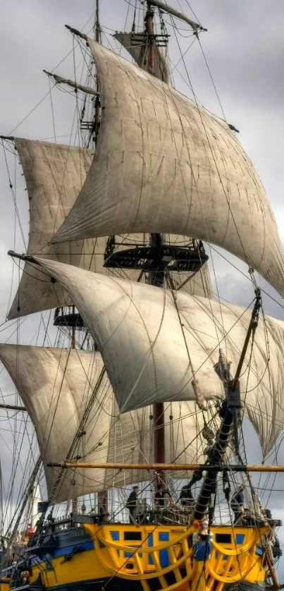 Majestic sailing ship with full sails on a cloudy ocean day.