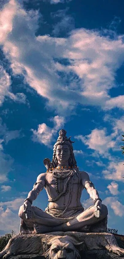 Majestic Shiva statue under a vivid blue sky with clouds.