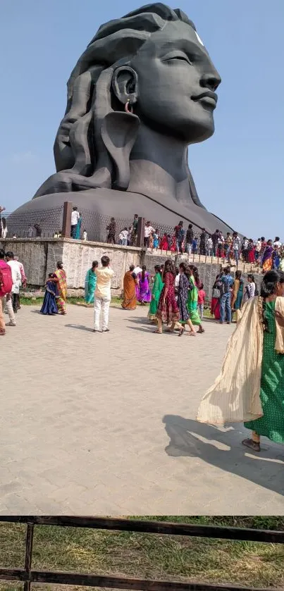 Majestic Shiva statue with visitors under a clear blue sky.