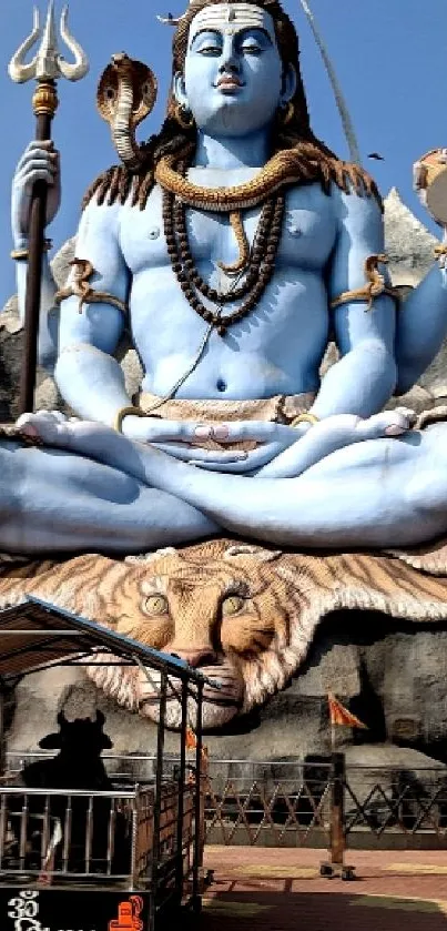 Majestic Shiva statue with blue sky backdrop for mobile wallpaper.