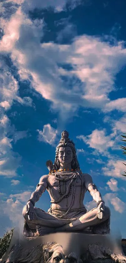 Majestic Shiva statue under blue and cloudy sky.